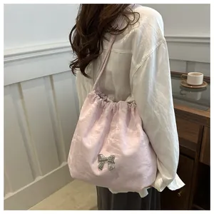 Detail of light pink pleated shoulder bag featuring a silver butterfly metallic ornament