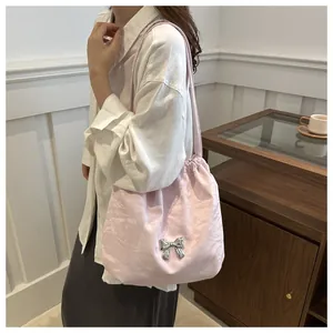 Detail of pink pleated crossbody bag featuring a silver butterfly charm and drawstring