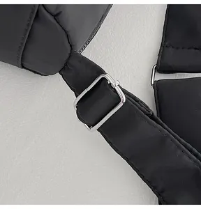 Close-up of silver metal adjustment buckle on black quilted crossbody bag strap