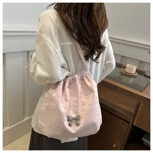 Detail of pink satin shoulder bag featuring textured pleats and a silver metal butterfly