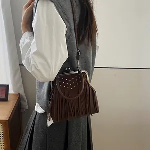 Vintage brown suede shell bag with fringe and rivets shown on a model's shoulder