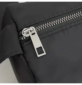 Detail of the high-quality black nylon fabric with silver metal zipper on small square bag