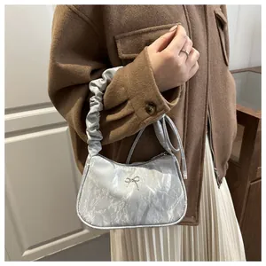 Silver glossy shoulder bag with metallic bow and scrunchie handle detail in style