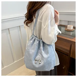 Close-up of light blue ruched shoulder bag with silver metal butterfly and drawstring