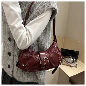 Détail du sac croissant rouge foncé avec rivets argentés et boucle métallique