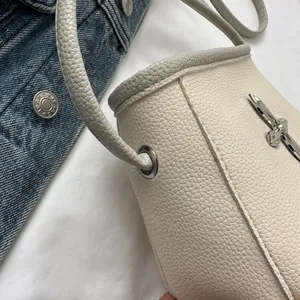 Détail du sac seau en cuir grainé blanc cassé avec œillets métalliques argentés et couture