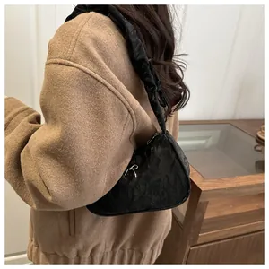 Detailed view of black pleated underarm bag with silver bow accent and knotted strap