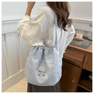 Close-up of light blue pleated bag featuring a silver butterfly charm and drawstring detail