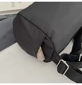 Detail of black nylon cylindrical crossbody bag showing side pocket and silver metal buckle