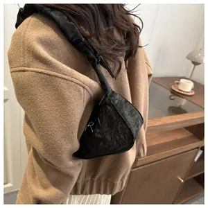 Chic black pleated underarm bag worn by model in a modern indoor lifestyle setting