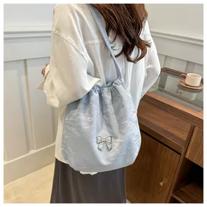 Detail of light blue pleated shoulder bag with metallic butterfly and drawstring closure