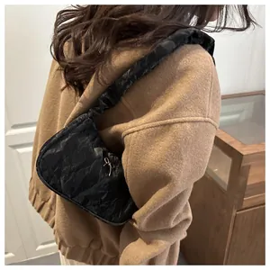 Close-up of black pleated underarm bag featuring a silver metal bow accent for women