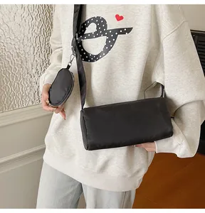 Detail of minimalist black nylon crossbody bag with detachable round coin purse on wide strap