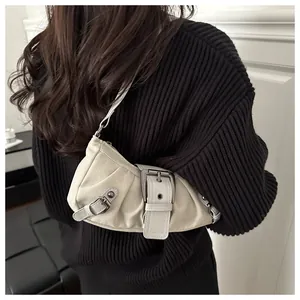 Dettaglio borsa a spalla a mezza luna beige con anelli metallici e texture a pieghe