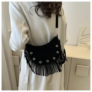 Detail of black crescent crossbody bag with gold rivets and long fringe tassels