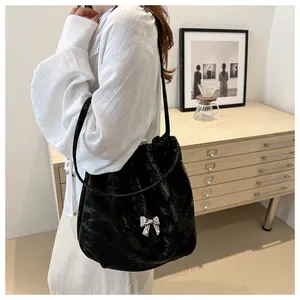 Detail of black pleated shoulder bag featuring a silver butterfly buckle and chain strap