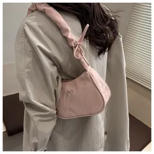Detail of pink pleated underarm bag with silver bow accent and scrunchie style strap