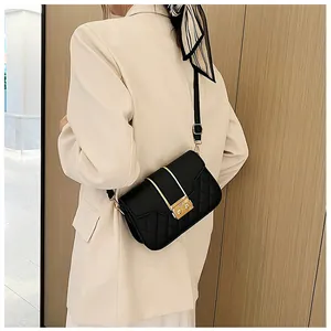 Close-up of black quilted shoulder bag with golden vertical metal trim and push-lock