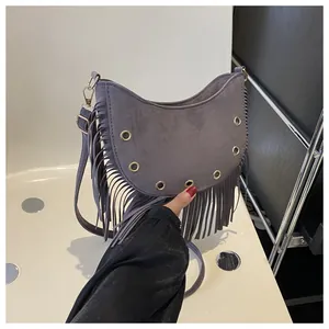 Detail of dark gray suede crescent bag featuring long tassels and gold metal eyelets