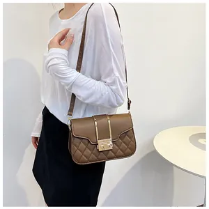 Detail of coffee brown quilted shoulder bag featuring gold metal clasp on white background