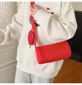 Close-up of a bright red cylindrical crossbody bag with a small round coin purse on strap