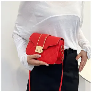Detailed view of red quilted leather crossbody bag with gold buckle and shoulder strap
