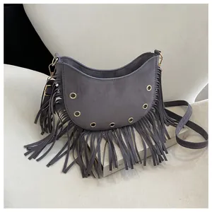 Detail view of grey crescent bag with long fringe tassels and golden metal eyelets