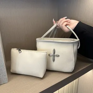 Ensemble sac seau en cuir grainé beige avec croix argentée sur support en bois élégant