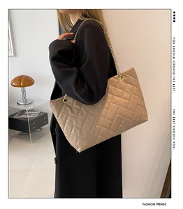 Detail of beige quilted tote bag with herringbone pattern and gold chain strap