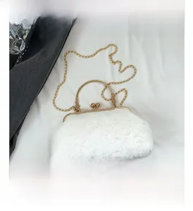 Detail of white faux fur handbag with golden kiss-lock closure and metal chain strap