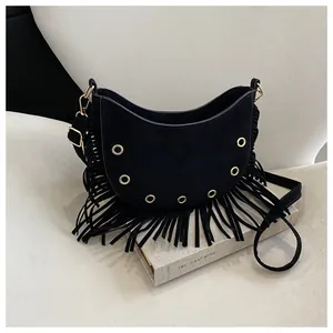Detail of black suede crescent bag with hanging tassels and gold metal eyelets decoration