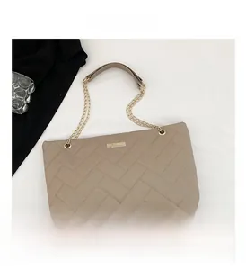Detail of herringbone quilted tote bag with gold chain strap and metal plate