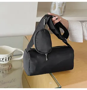 Detail of black nylon barrel shoulder bag with a mini pouch on a lifestyle background