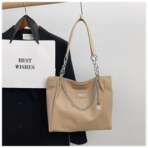 Close-up of beige pebble leather tote bag with silver chain straps and metal charm