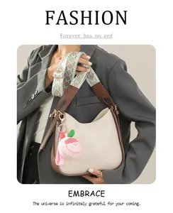Borsa a tracolla beige chic con bordo marrone e tracolla a motivi indossata su abito grigio