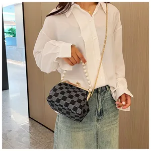 Fashionable checkered crossbody bag with pearl handle and metal chain shown on model