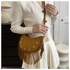 Close-up of bohemian ginger suede saddle bag featuring long fringe and gold metal eyelets
