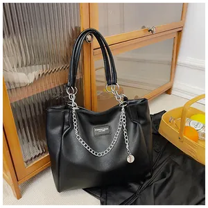 Detail of black pebbled tote bag with silver chain, pendant and fashion metal nameplate