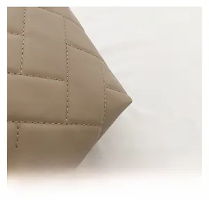 Close-up of khaki quilted leather texture and fine stitching on the large tote bag