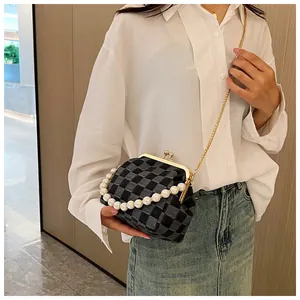 Detail of a gray plaid crossbody bag featuring a large pearl handle and gold chain strap