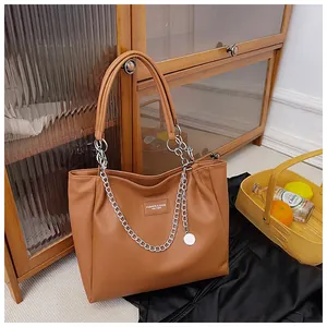 Detail view of large brown faux leather tote bag with silver chain and textured finish