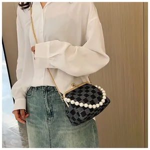 Detail of checkered crossbody bag featuring pearl handle and gold clasp closure