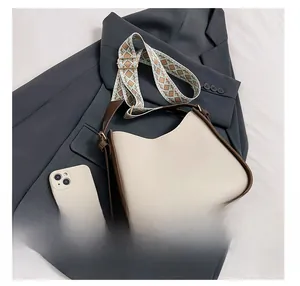 Dettaglio di borsa a tracolla beige a contrasto con cinturino in tessuto stile etnico