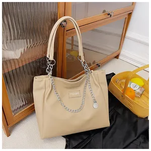 Close-up of beige lychee grain faux leather tote bag with stylish silver metal chain detail