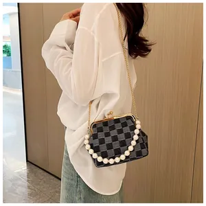 Detail of checkered crossbody bag with pearl handle and gold chain on white outfit