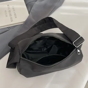 Minimalist black nylon shoulder bag with adjustable strap and multiple inner pockets