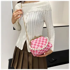 Detail of pink checkerboard fabric bag with pearl handle and golden clasp closure