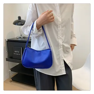 Dunkelblaue Achseltasche aus Leder mit Litschistruktur getragen zu einer weißen Bluse