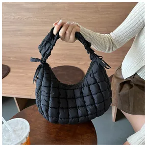 Détail du sac matelassé noir montrant les poignées plissées et les nœuds décoratifs