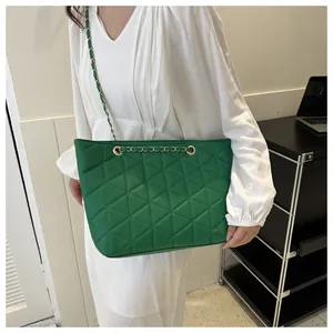 Sac cabas matelassé vert avec chaîne dorée porté par un mannequin en style épuré